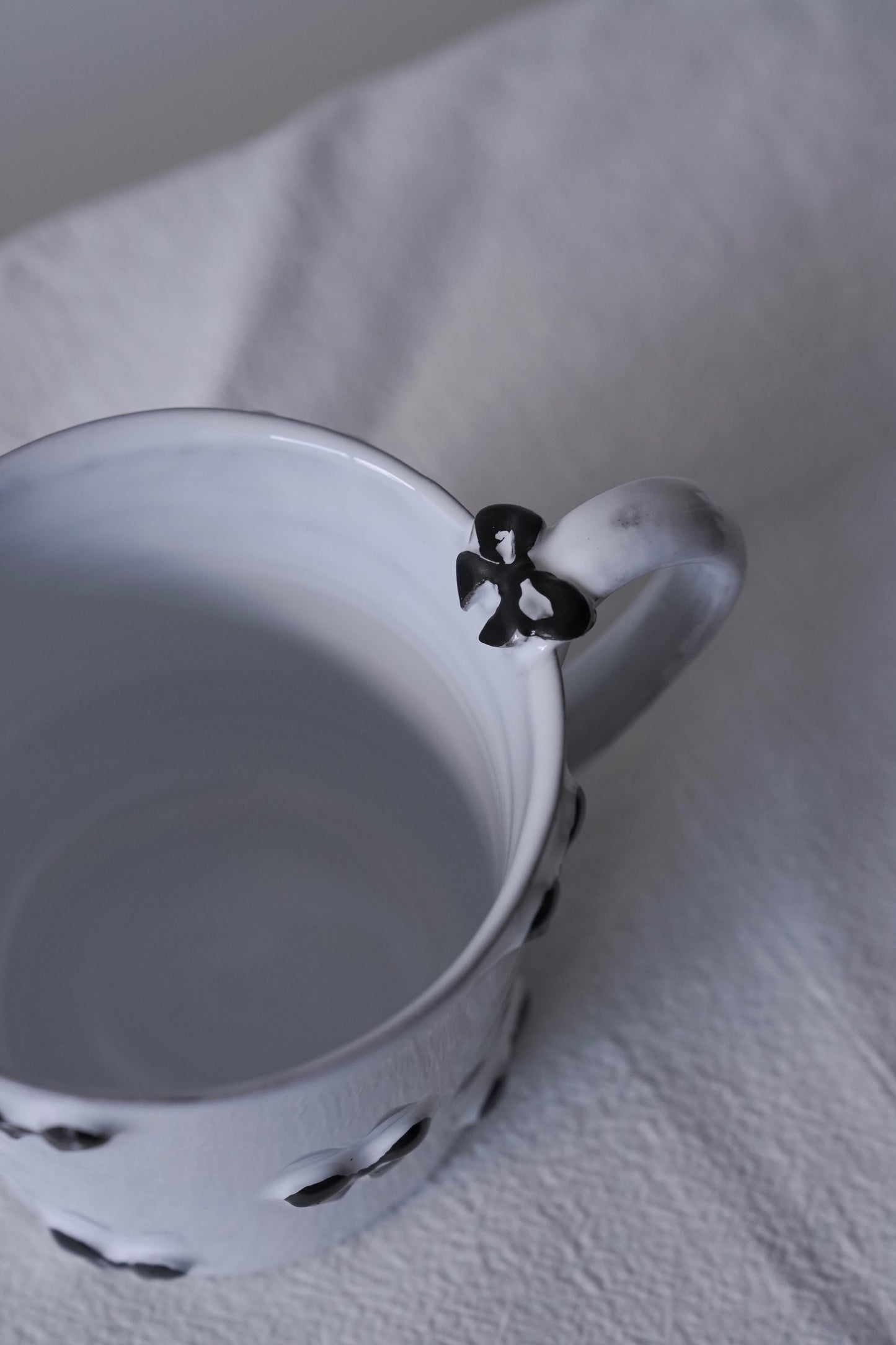 Close up of Carron Paris Noeud Noeud mug in black feauring hand-painted black bow handle detail.