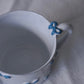 Close up of CARRON Paris handmade white ceramic Nœud-Nœud Trianon mug featuring a hand-painted sky blue bow handle detail
