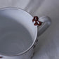 Close-up of Carron Paris Noeud Noeud Mug with handle featuring a hand-painted deep bordeaux bow handle detail.