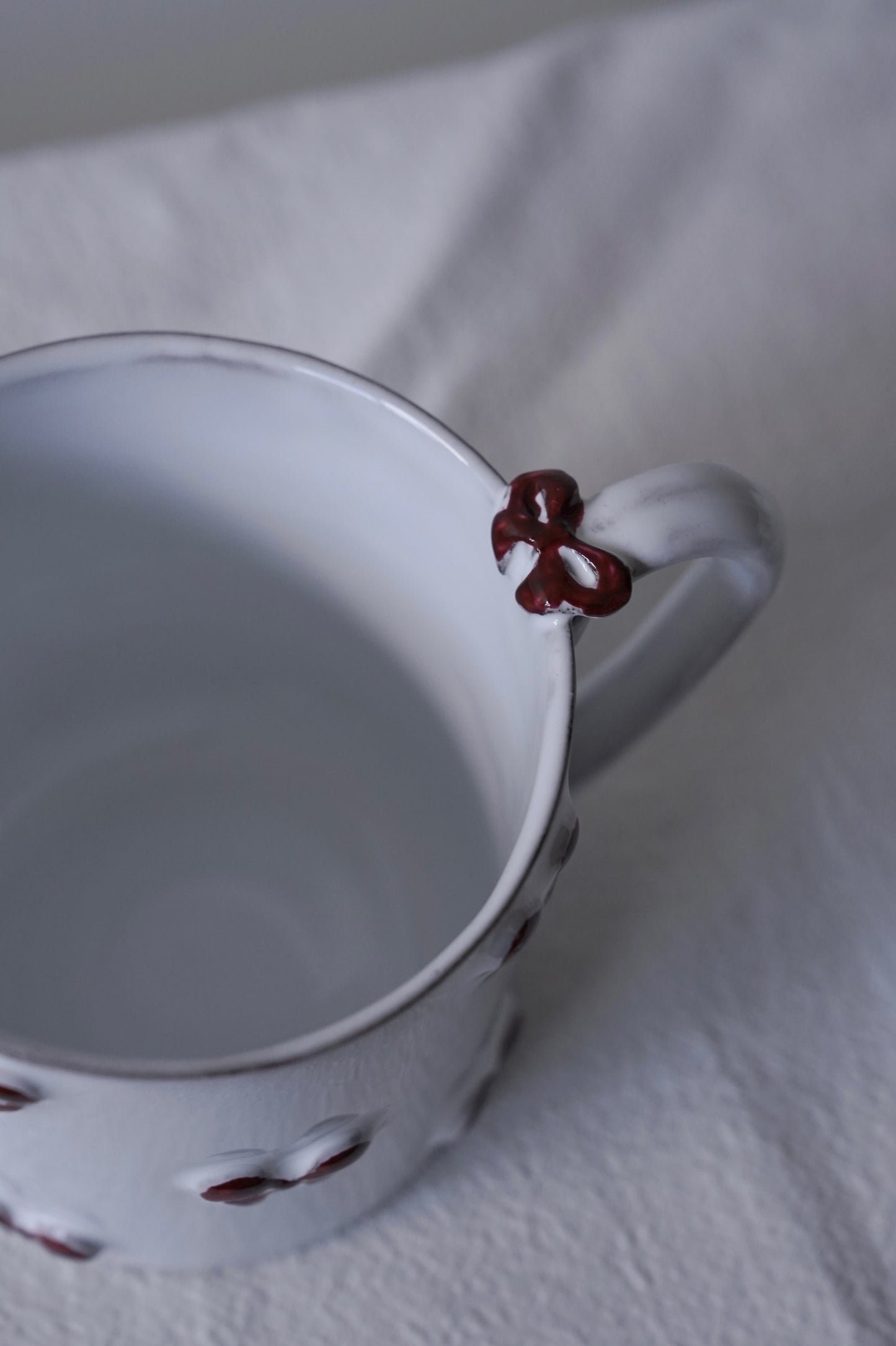 Close-up of Carron Paris Noeud Noeud Mug with handle featuring a hand-painted deep bordeaux bow handle detail.
