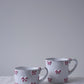 CARRON Paris handmade white ceramic Nœud-Nœud Trianon mug featuring a hand-painted dusty rose bow detail, available in small and medium.