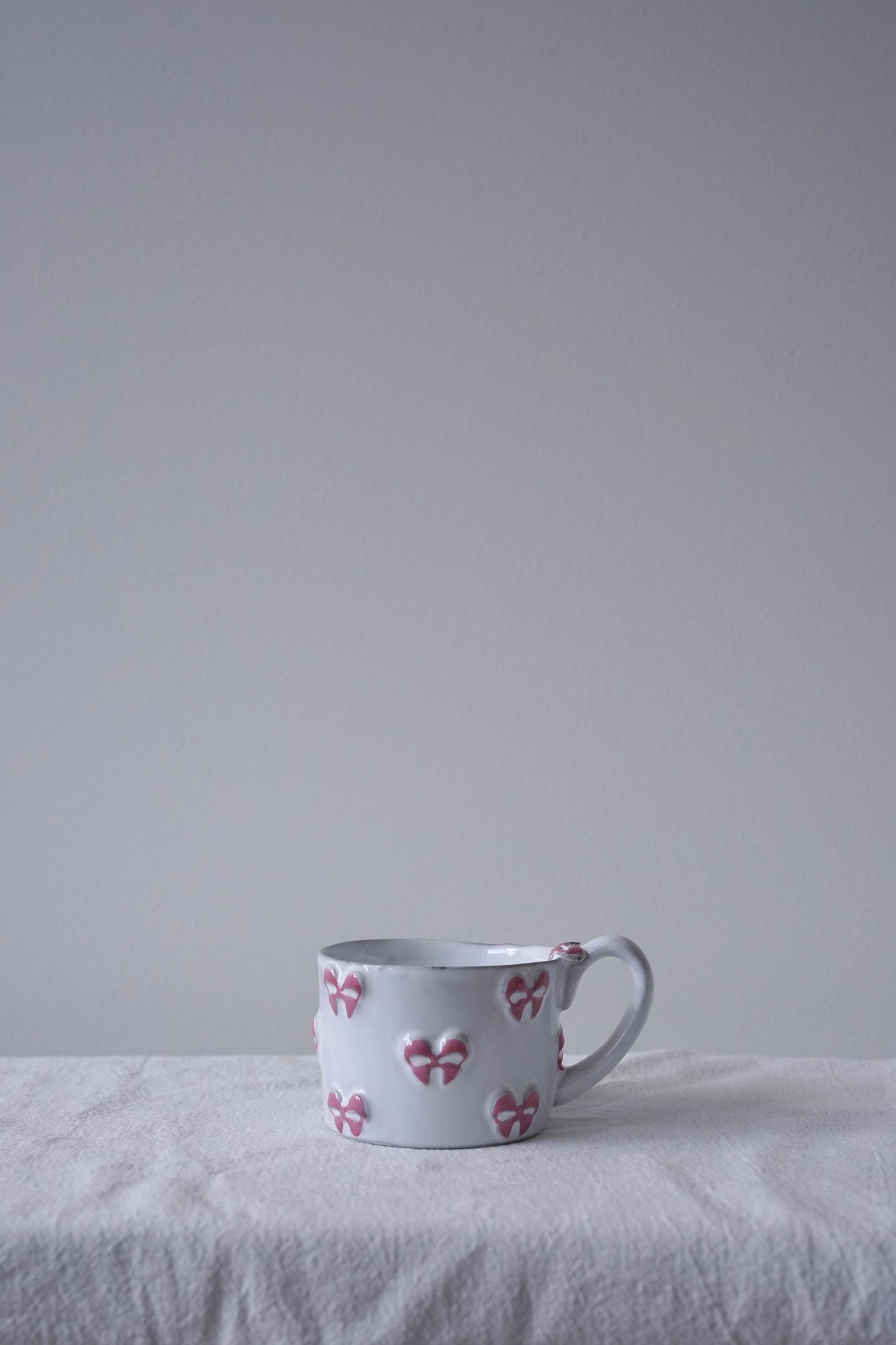 CARRON Paris handmade white ceramic Nœud-Nœud Trianon mug in small, featuring a hand-painted dusty rose bow detail.