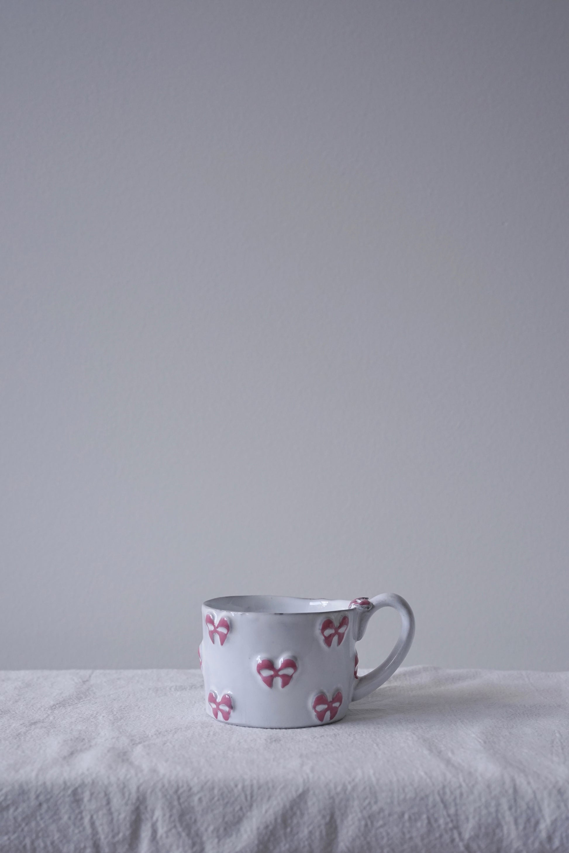CARRON Paris handmade white ceramic Nœud-Nœud Trianon mug in small, featuring a hand-painted dusty rose bow detail.