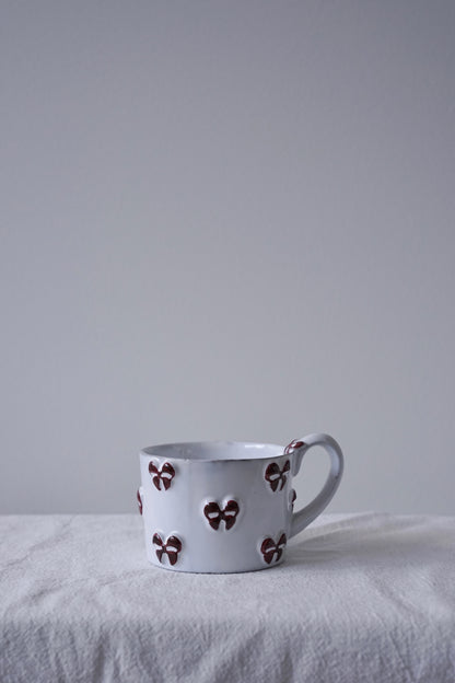 CARRON Paris handmade white ceramic Nœud-Nœud Trianon mug in small size featuring a hand-painted deep bordeaux bow handle detail