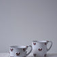 CARRON Paris handmade white ceramic Nœud-Nœud Trianon mug featuring a hand-painted deep bordeaux bow handle detail, in small and medium sizes. 