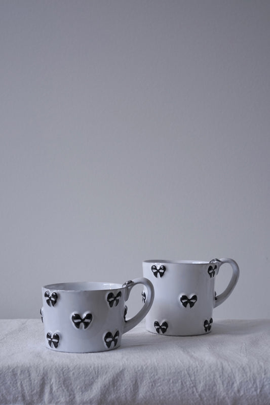 CARRON Paris handmade white ceramic Nœud-Nœud Trianon mug featuring a hand-painted black bow detail, available in small and medium. 