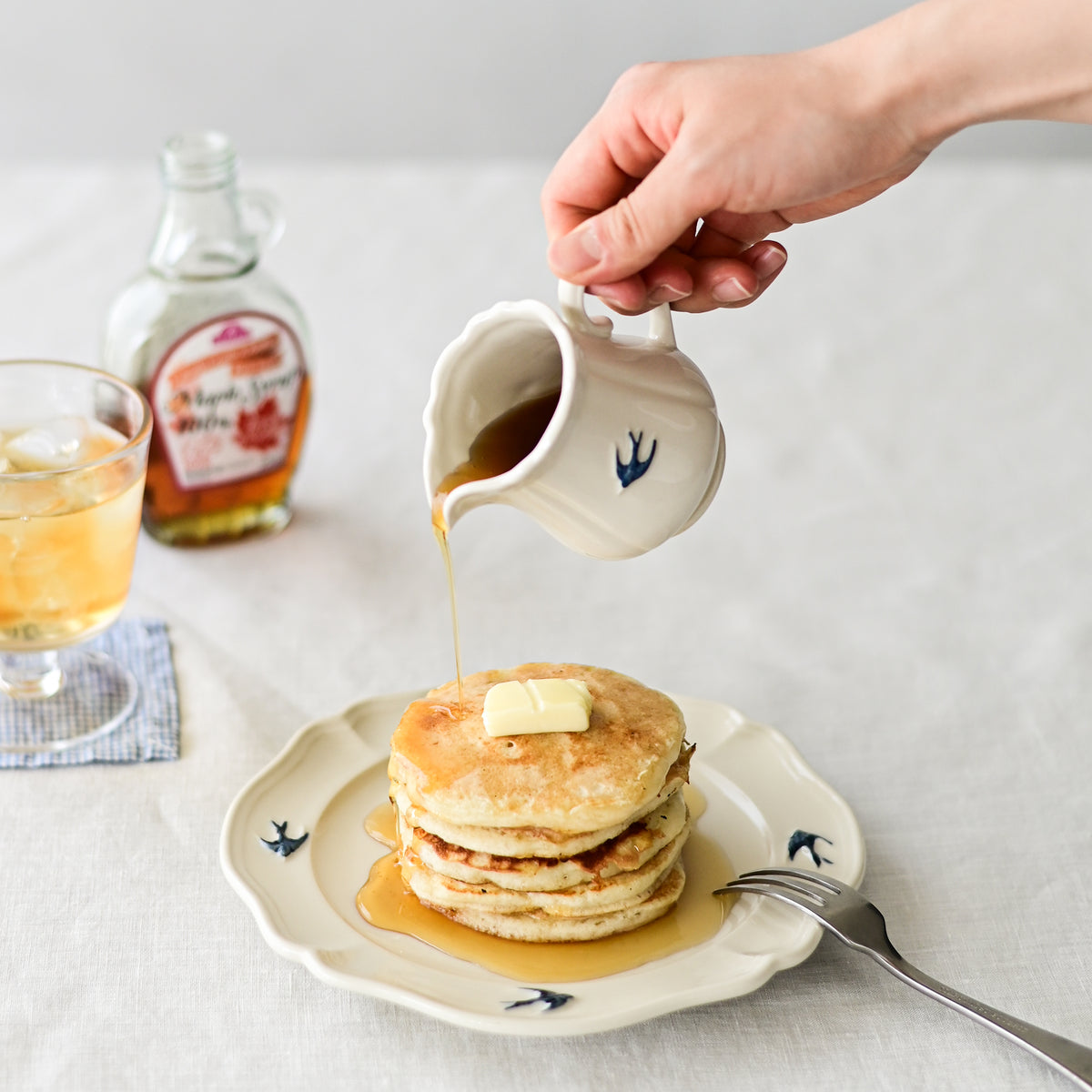 Studio M Early Bird small creamer pouring maple syrup onto a plate of pancakes