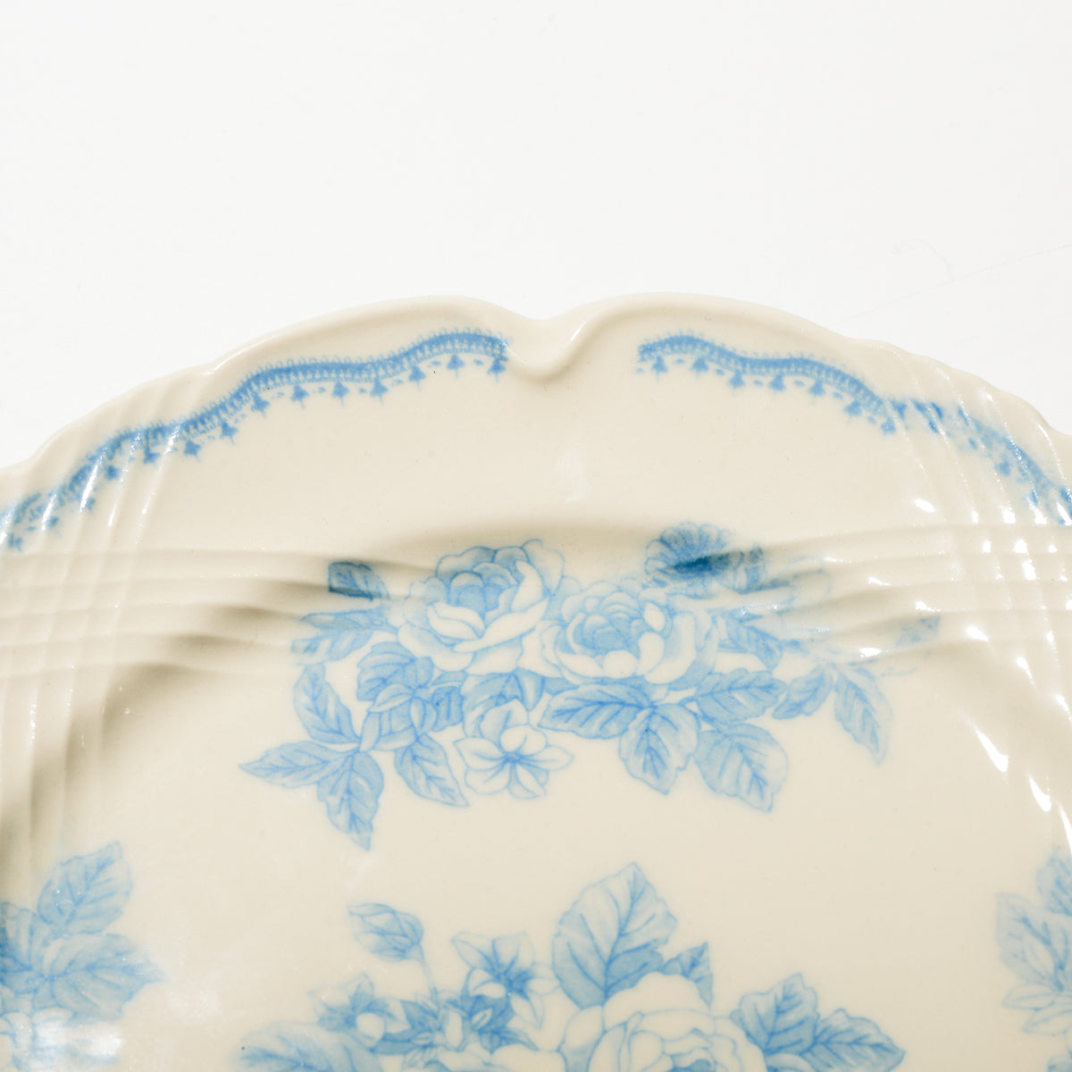 Close-up of hand applied blue rose copperplate transfer and carved relief rim on Studio M plate