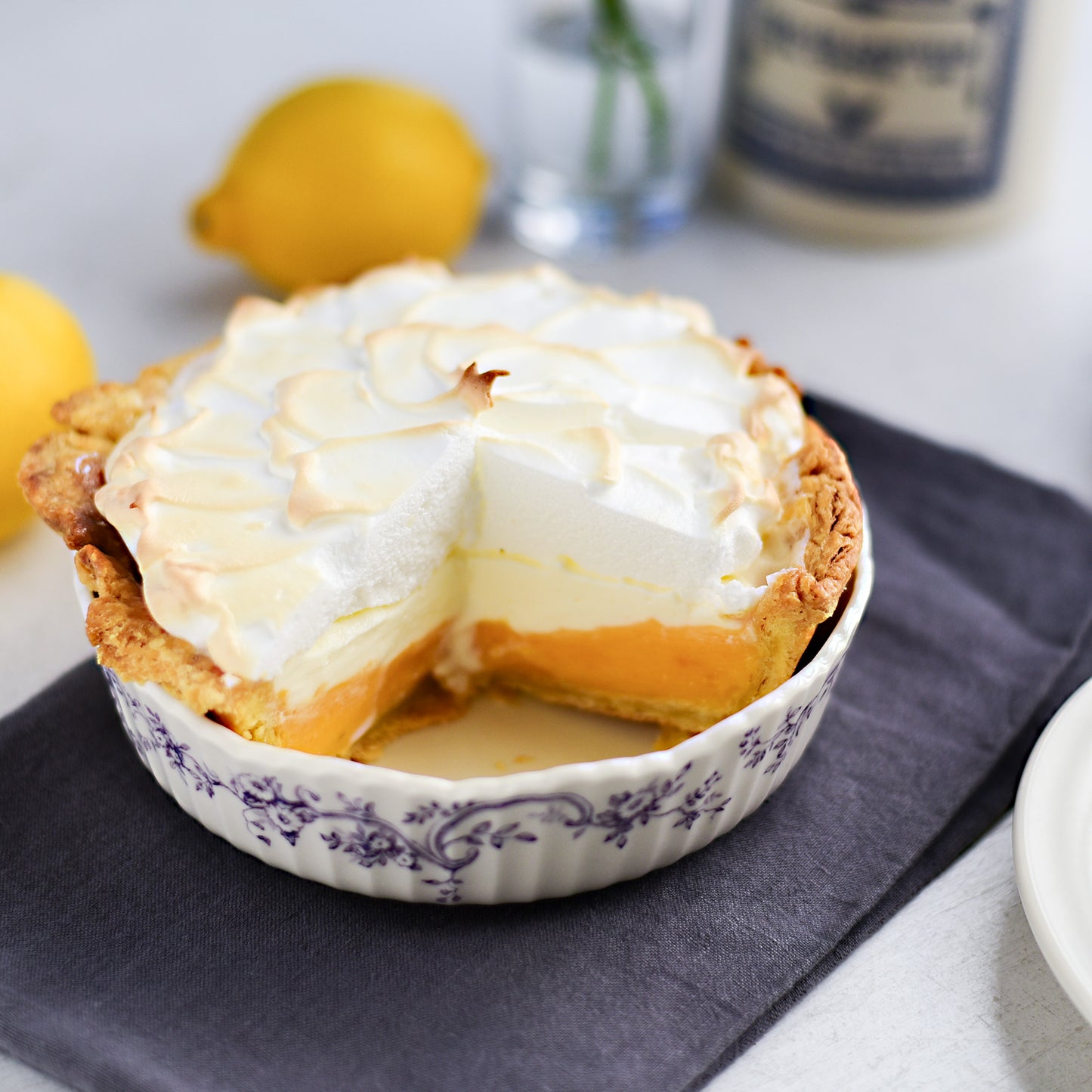 Studio M' Audrey Cake Pan in porcelain, featuring a scalloped lace-like rim and an English garden-inspired floral relief pattern.