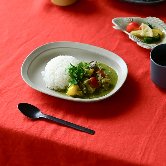 Studio M Karil 25cm oval earthenware plates in ecru colour serving curry and rice on a red table cloth.