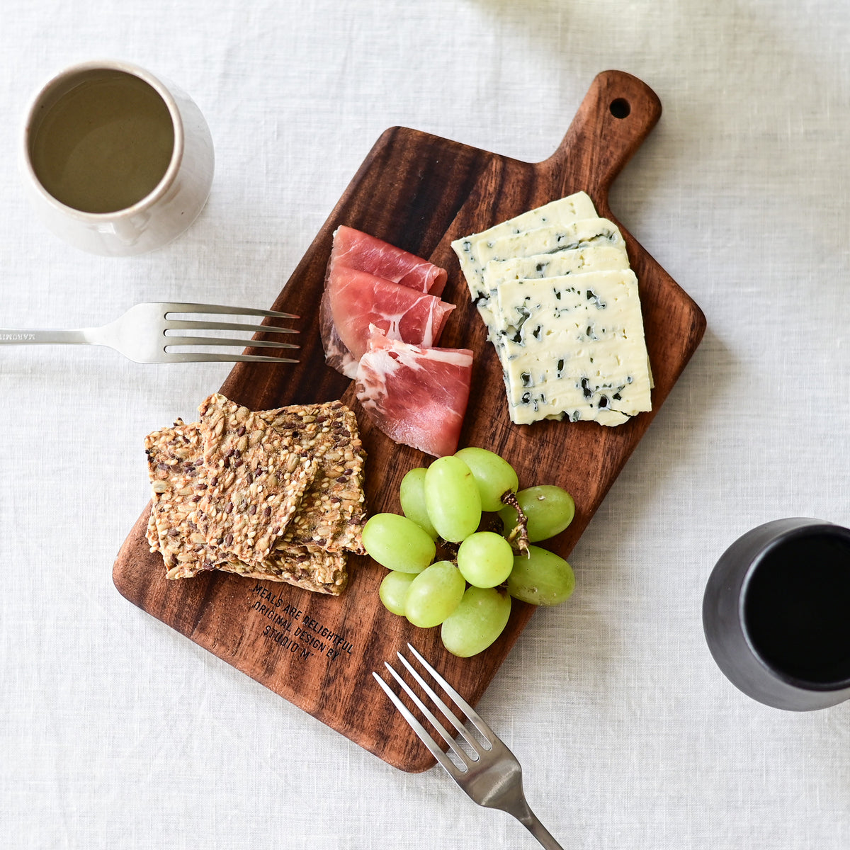 Studio M Japanese solid walnut cutting board collection in oblong medium size, serving a cheese platter. 