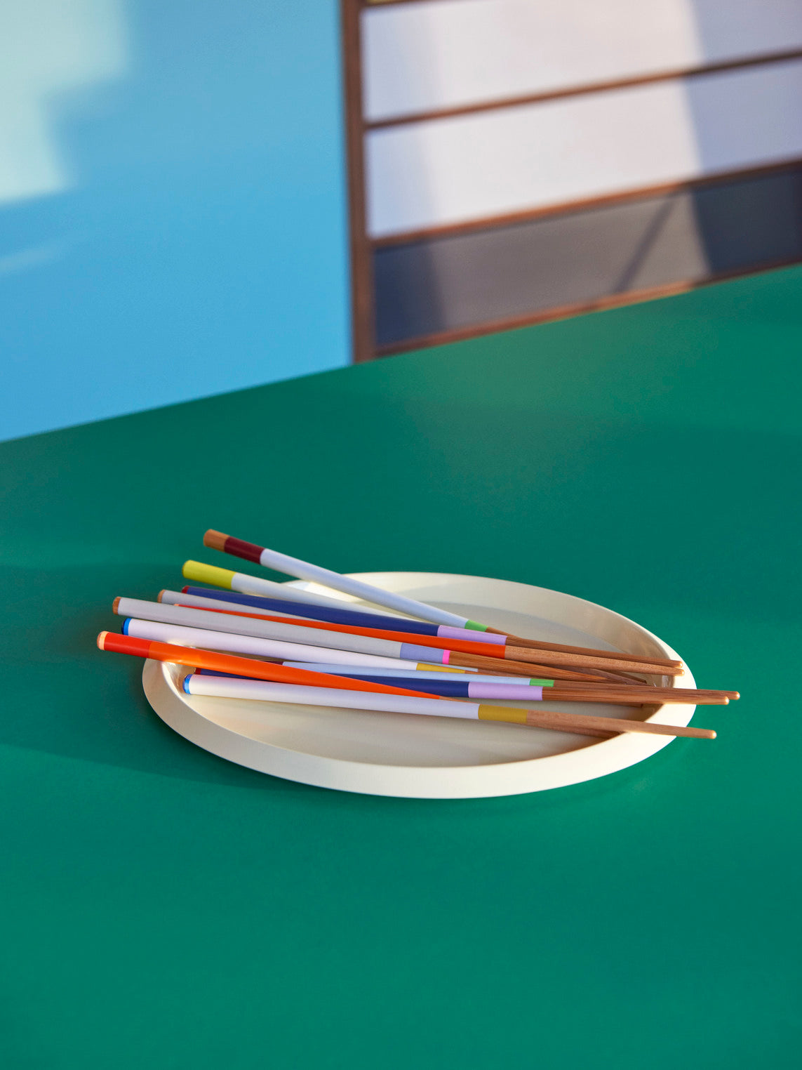A lifestyle shot of four pairs of HAY Colour Sticks crafted from bamboo, showcasing their vibrant, multicolored lacquered handles arranged on a clean surface.