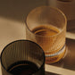 Close-up of ferm LIVING Ripple clear and grey glass tumblers on table.