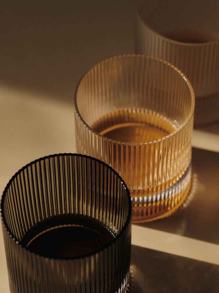 Close-up of ferm LIVING Ripple clear and grey glass tumblers on table.