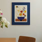 a lifestyle photo of the art print Colourful Bunch in Blue Vase by Frankie Penwill, exclusively created for The Poster Club, in a blue wooden frame with a blue paper cutout. 