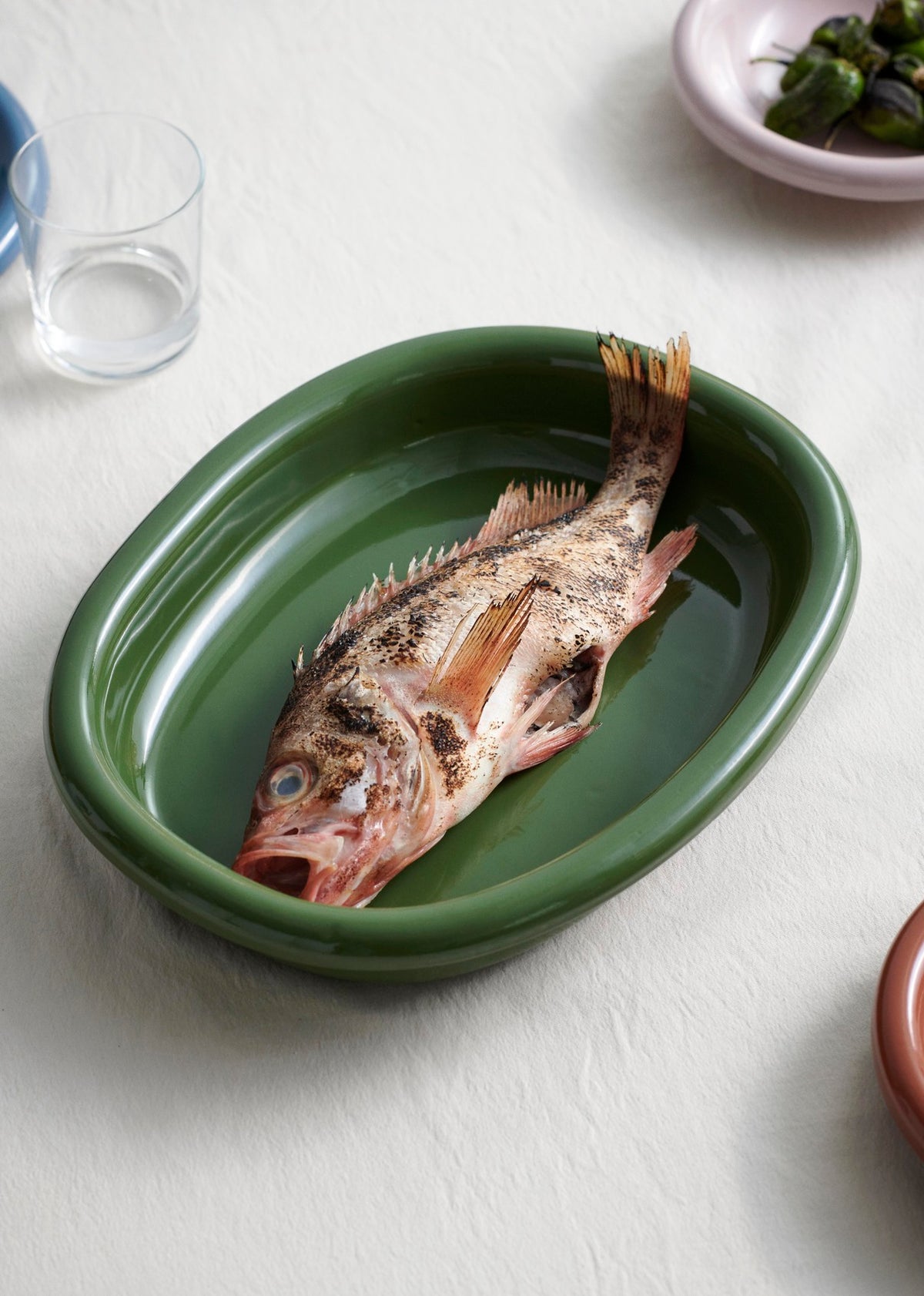HAY Barro large green oval dish serving roasted feast on contemporary dining table, serving a fish.
