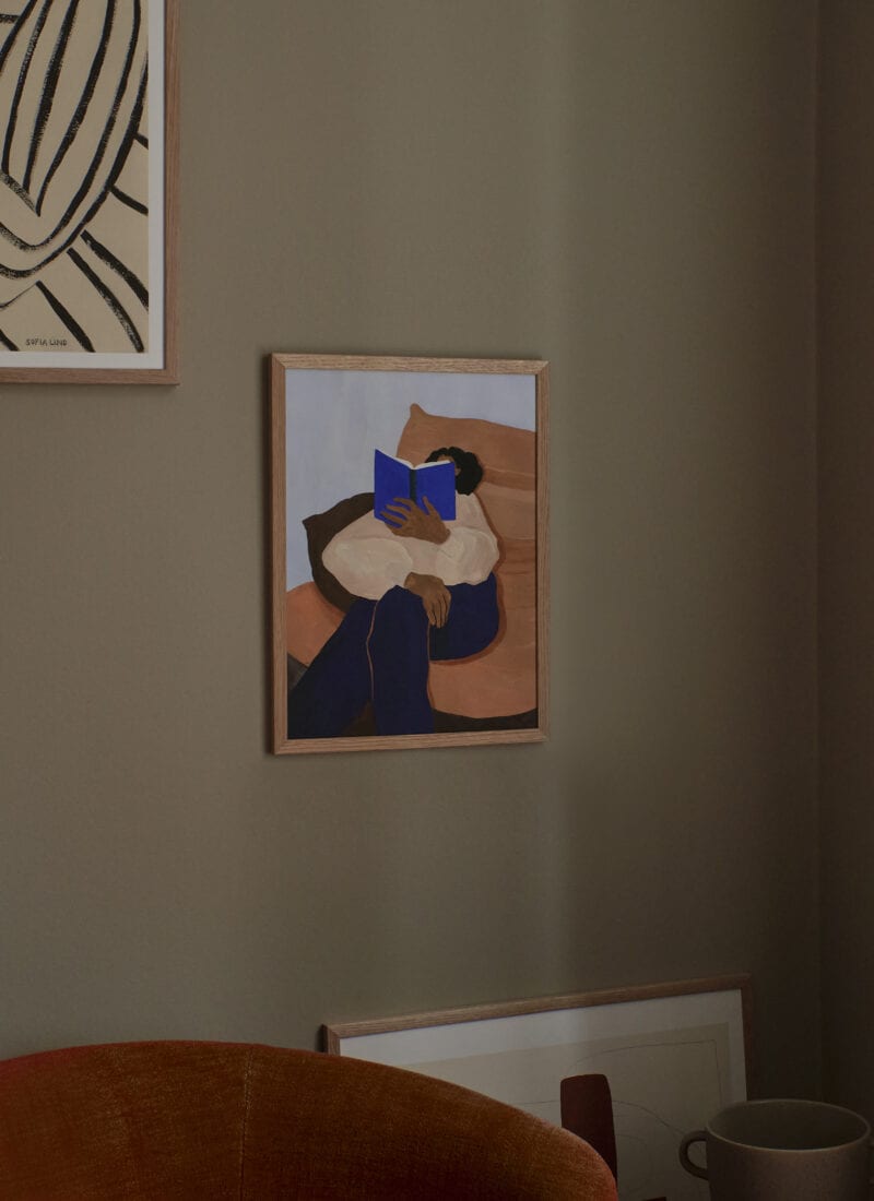 A lifestyle photo of the art print The Togo by Hanna Peterson in a light wooden frame, in a Scandinavian interior,.