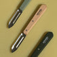 Opinel N115 French stainless steel vegetable peelers in assorted wooden handles on HAY cutting board.
