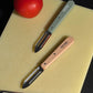 Opinel N115 peelers with a fresh tomato on Hay cutting board.