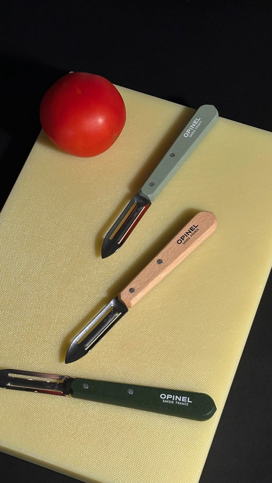 Opinel N115 peelers with a fresh tomato on Hay cutting board.