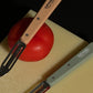 Opinel N115 peeler in Natural and Khaki on Hay cutting board.