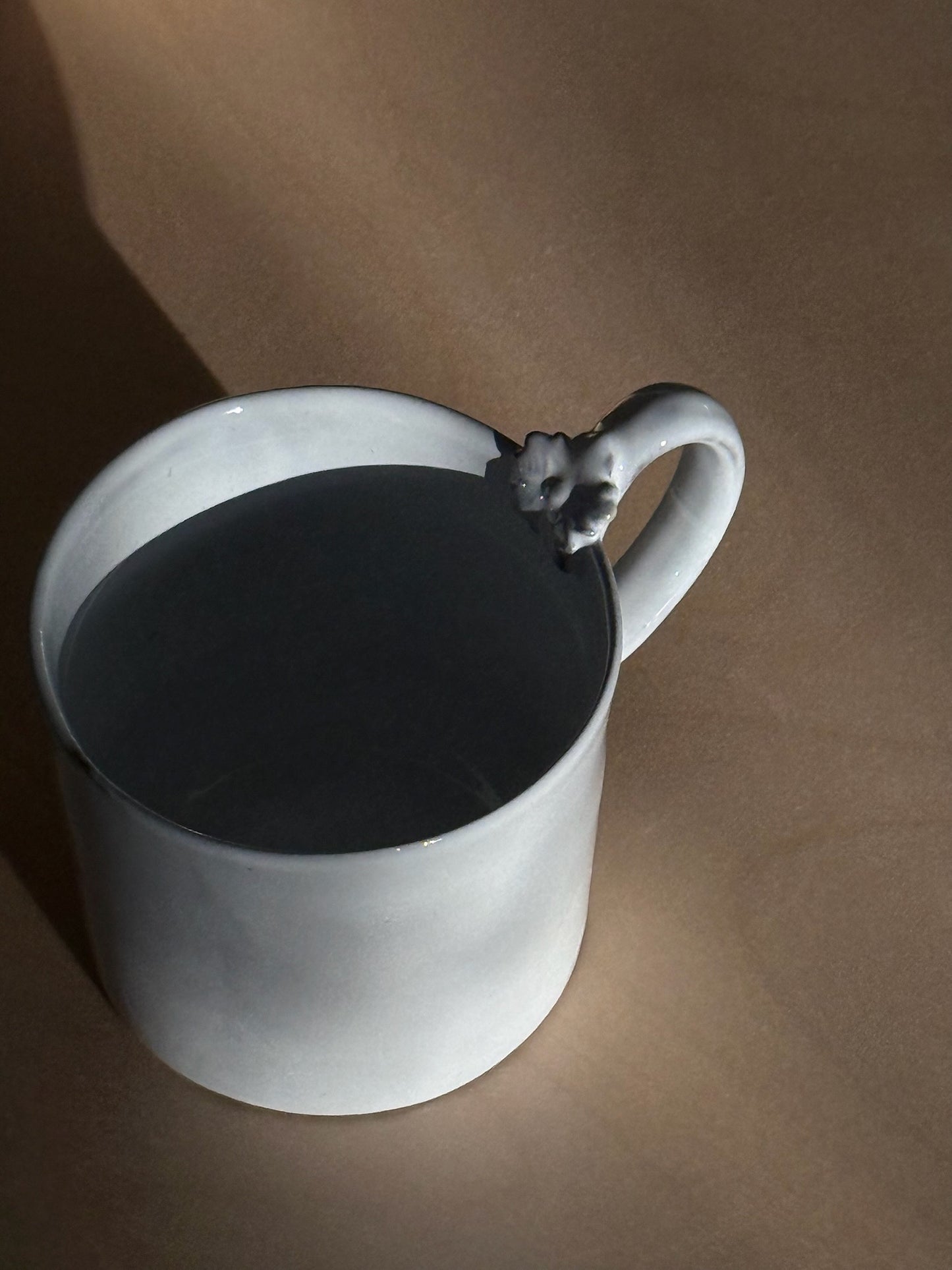 A closeup shot of Carron Paris ceramic mug with a unique sculpted flower on the handle