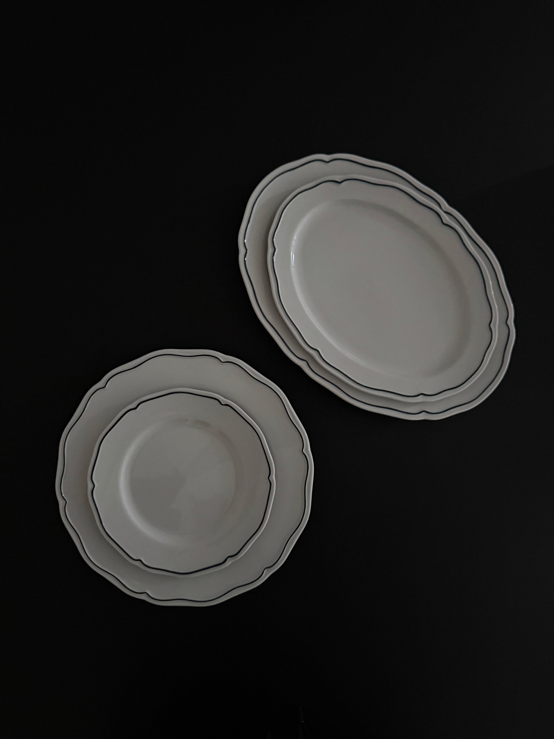 Tuxton Charleston round dinner plates and oval platters in American White with embossed scalloped edges.