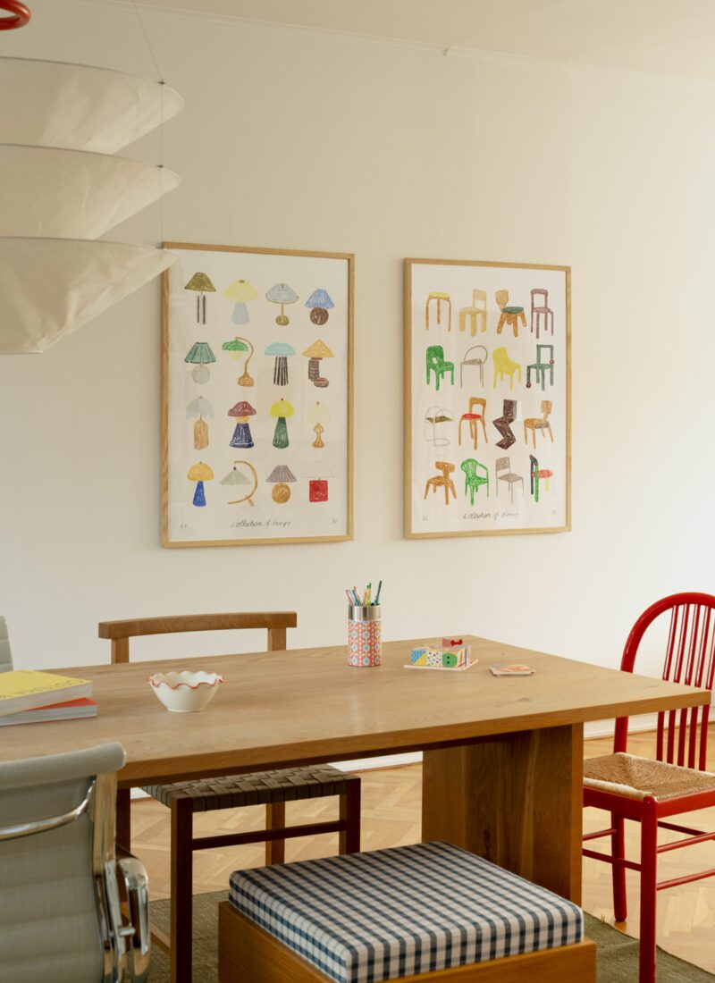 A lifestyle photo of art print A Collection of Chairs by Isabelle Vandeplassche, exclusively for The Poster Club, in a light wooden frame, paired with the art print A Collection of Lamps. 