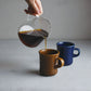 Kinto SCS Slow Coffee Style 600ml coffee server pouring coffee into a mug.