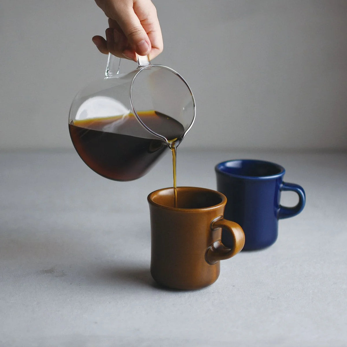 Kinto SCS Slow Coffee Style 600ml coffee server pouring coffee into a mug.