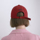 Back view of a woman wearing HÔTEL827 Sun Kissed baseball cap in chilli paring with pink top.