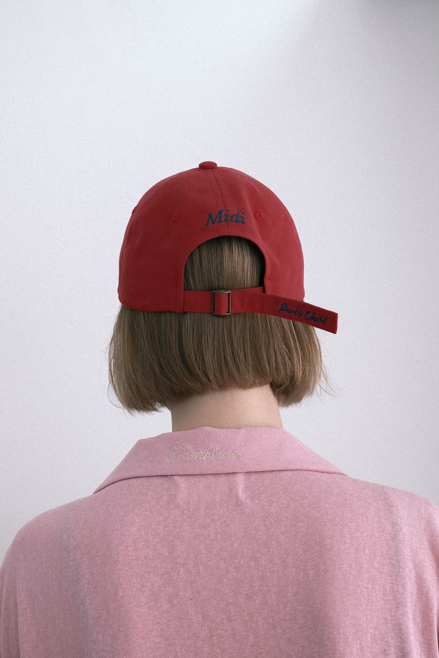 Back view of a woman wearing HÔTEL827 Sun Kissed baseball cap in chilli paring with pink top.
