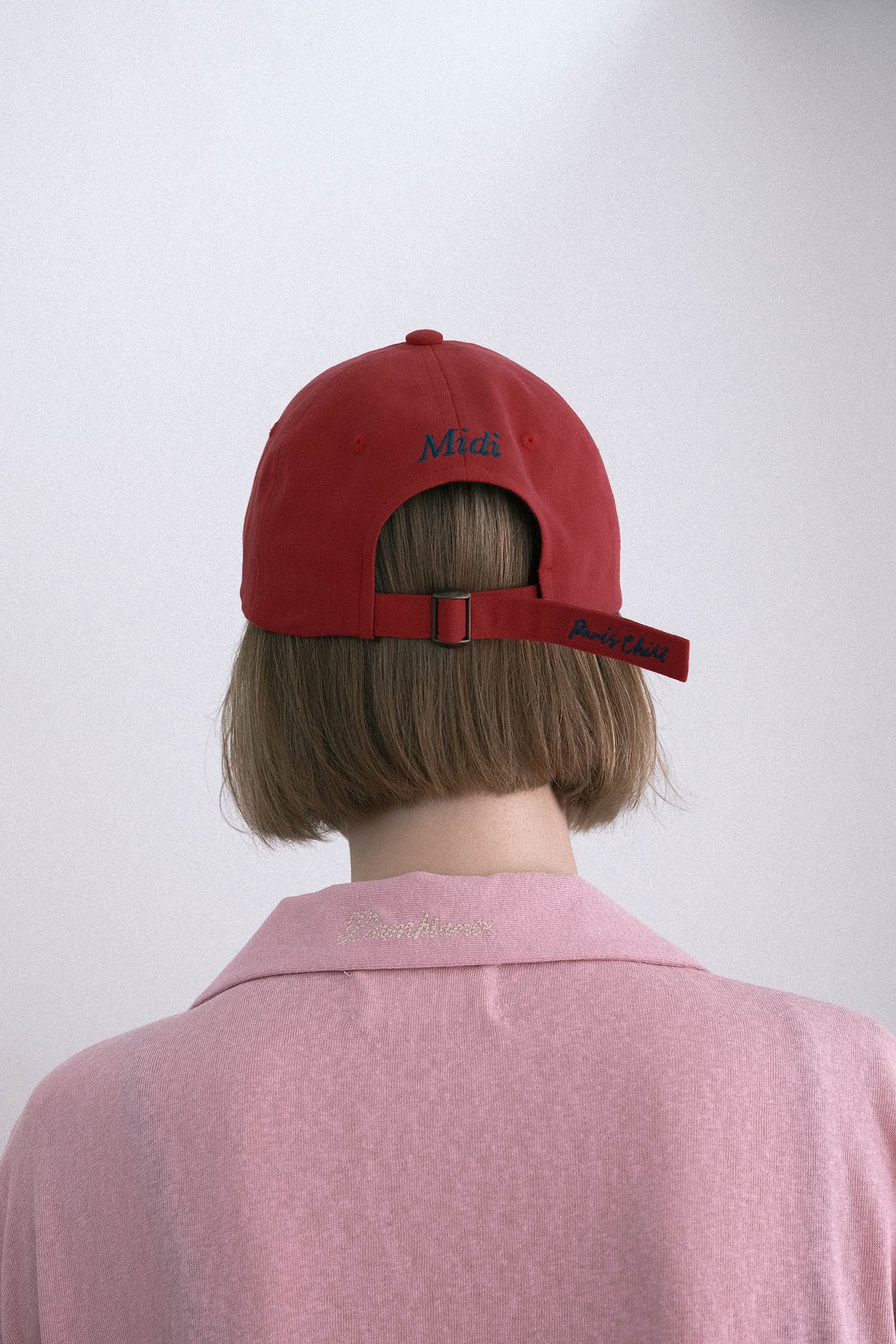 Back view of a woman wearing HÔTEL827 Sun Kissed baseball cap in chilli paring with pink top.