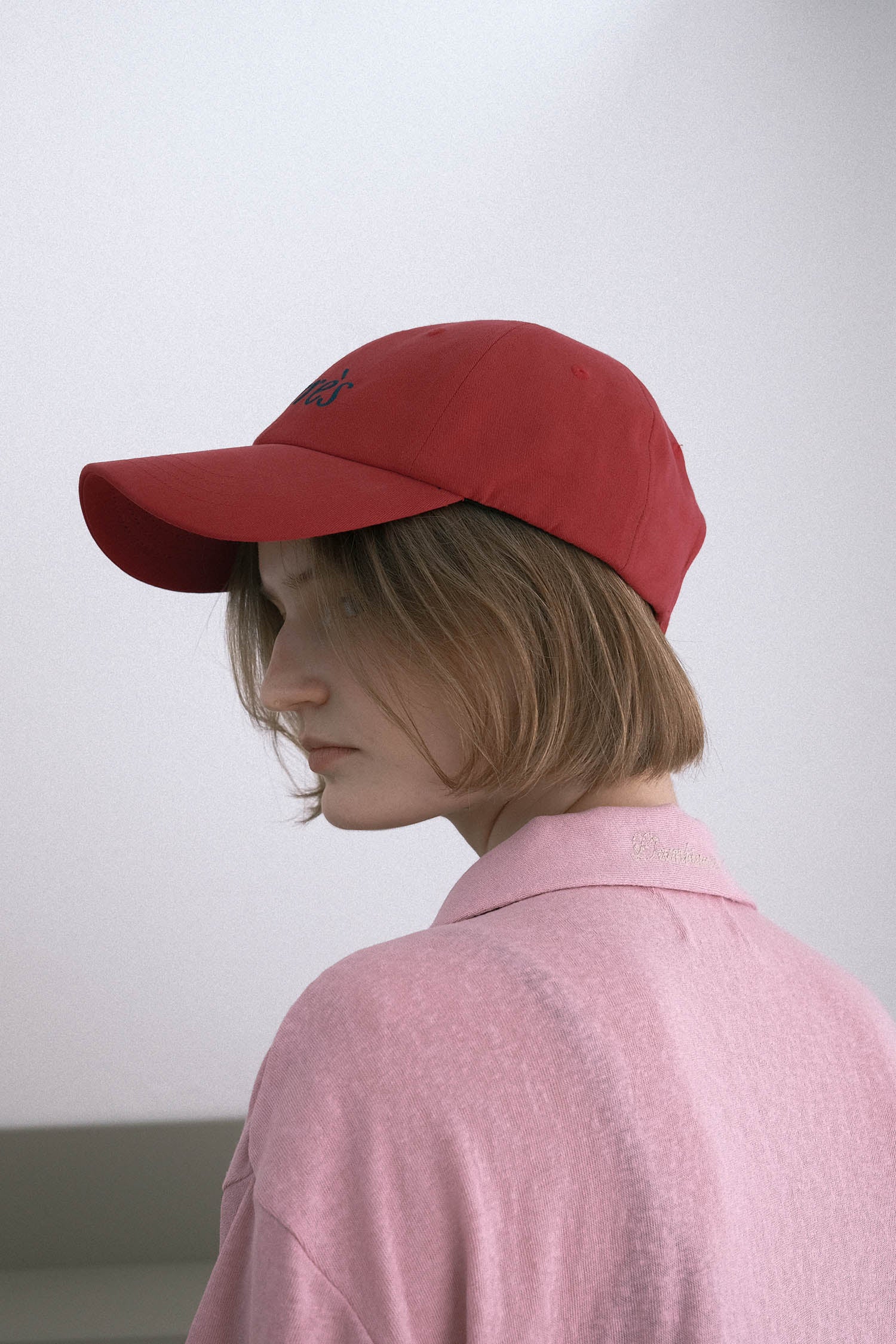 Side view of a woman wearing HÔTEL827 Sun Kissed baseball cap in chilli paring with pink top. 