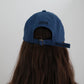 View of the back of the Hotel827 Sun Kissed baseball cap in blue, showcasing "Midi" letter as well as the brand logo on the strap.