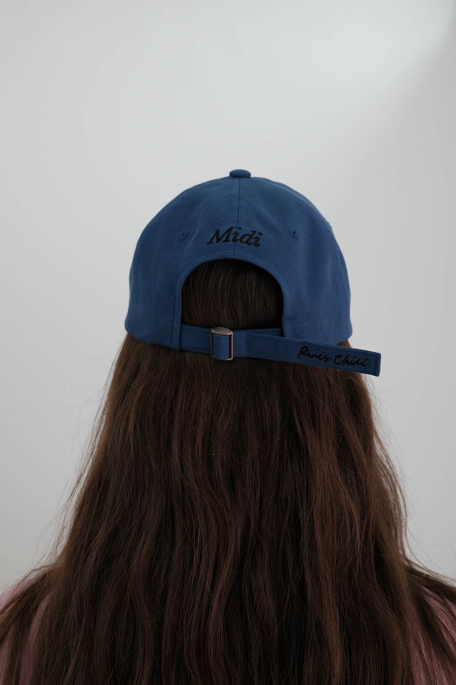 View of the back of the Hotel827 Sun Kissed baseball cap in blue, showcasing "Midi" letter as well as the brand logo on the strap.