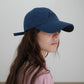 A side-view of woman wearing HÔTEL827 Sun Kissed blue baseball cap in casual street style
