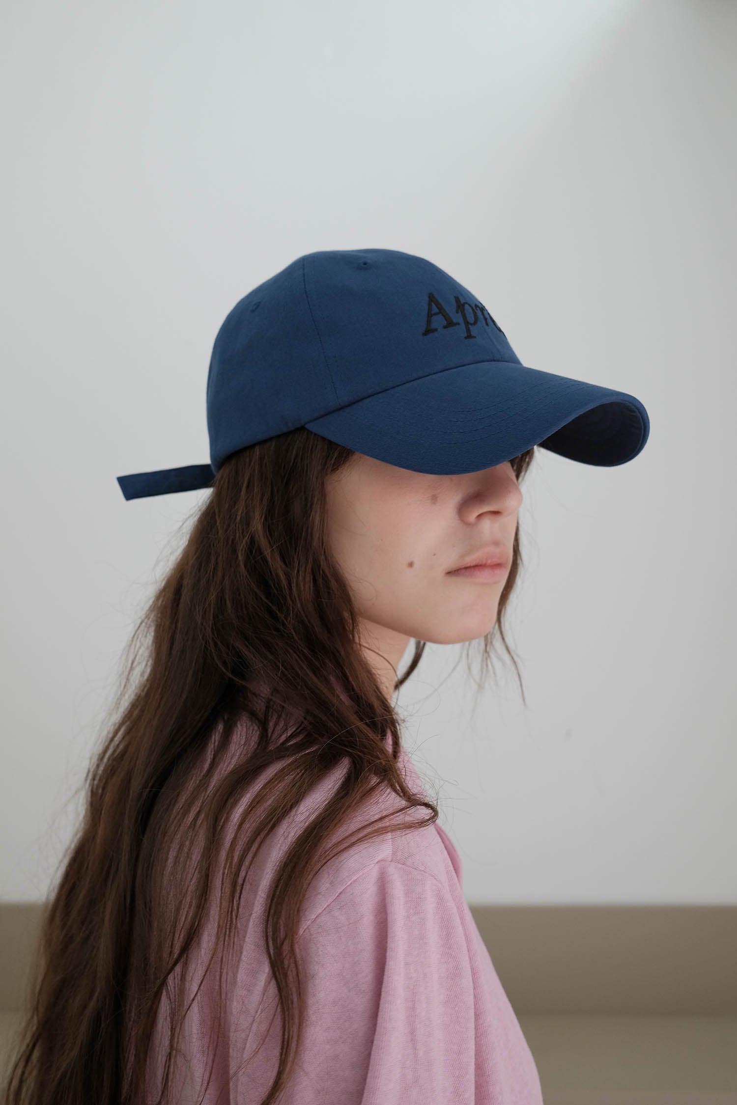 A side-view of woman wearing HÔTEL827 Sun Kissed blue baseball cap in casual street style