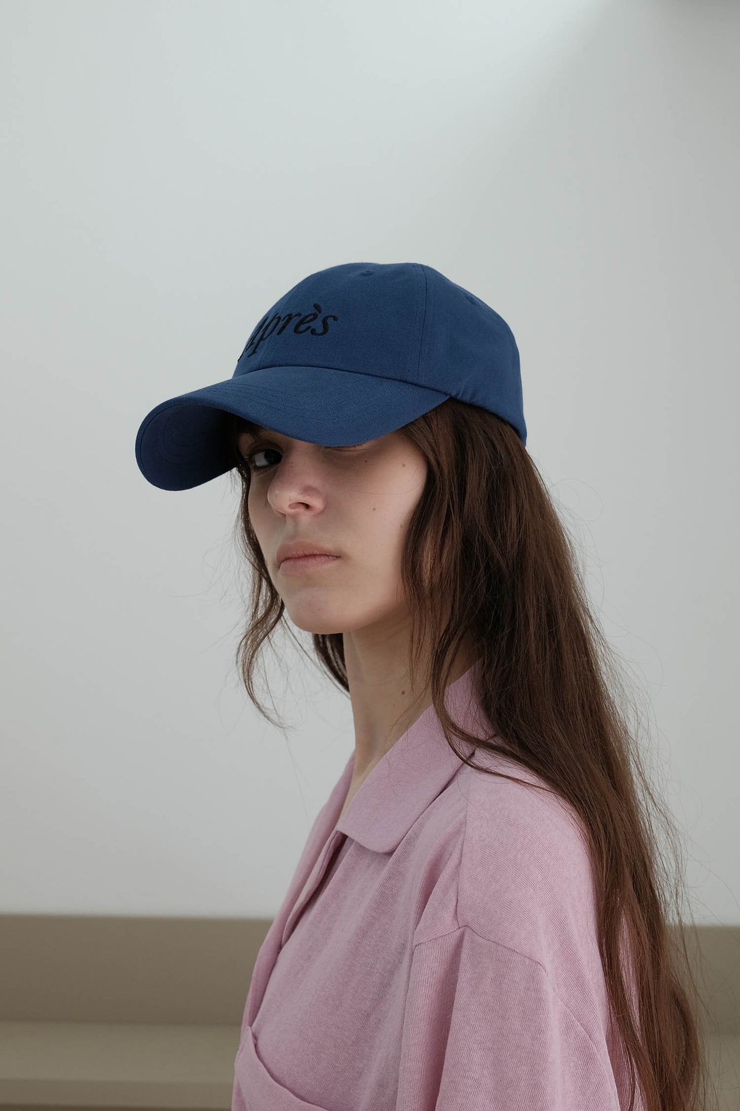A side-view of woman wearing HÔTEL827 Sun Kissed blue baseball cap in casual street style from the left. 