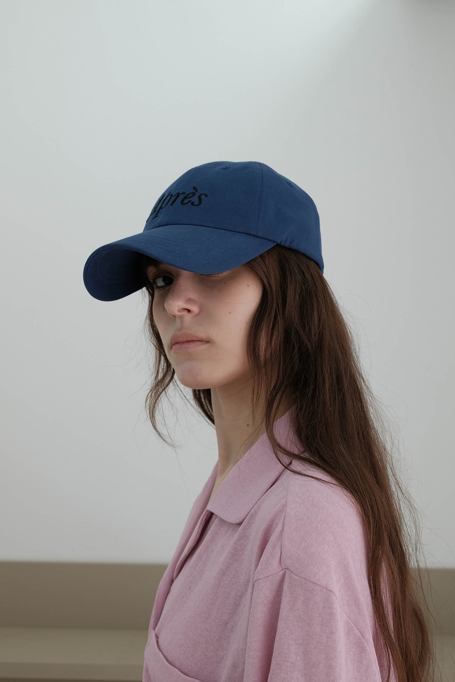 A side-view of woman wearing HÔTEL827 Sun Kissed blue baseball cap in casual street style from the left. 