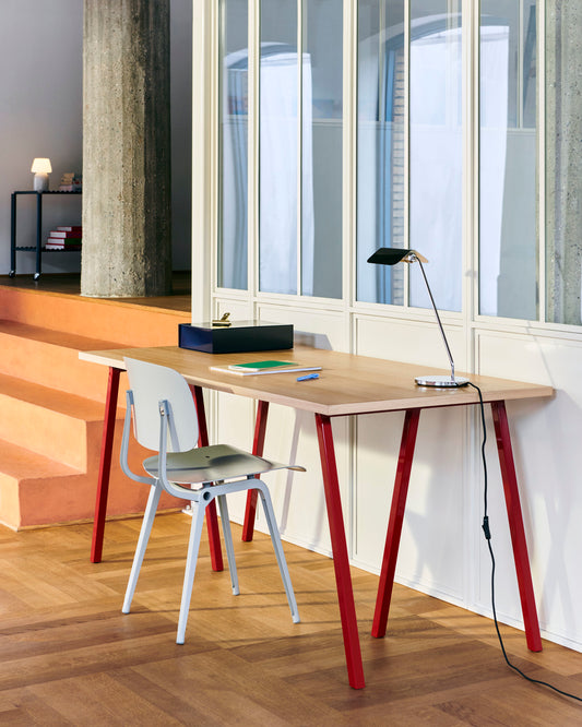 Hay Apex Desk lamp in iron black on a wooden desk.