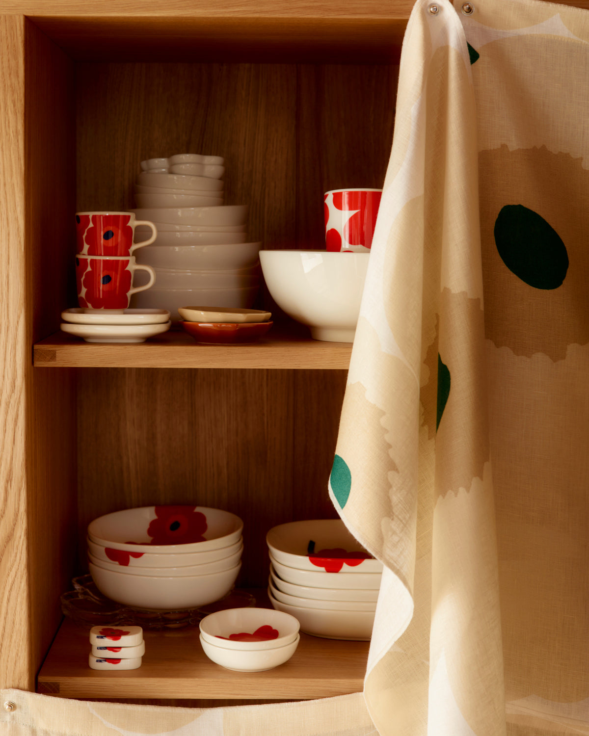 Marimekko Oiva Unikko stonewares in vibrant white red and blue stacked on a open shelf.