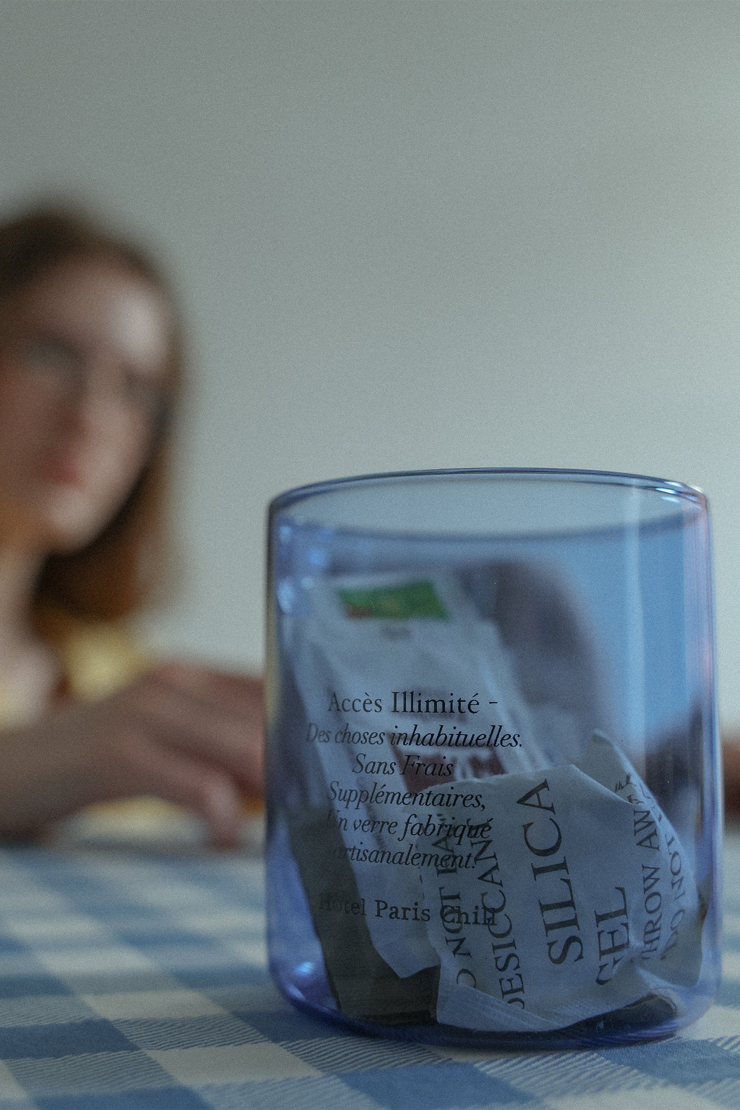 Close-up of HÔTEL827 blue glass storage jar on dining table holding tea bags.