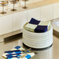 Stacked Hay 18cm Barro plates in off-white, with napkins on top on a kitchen bench.