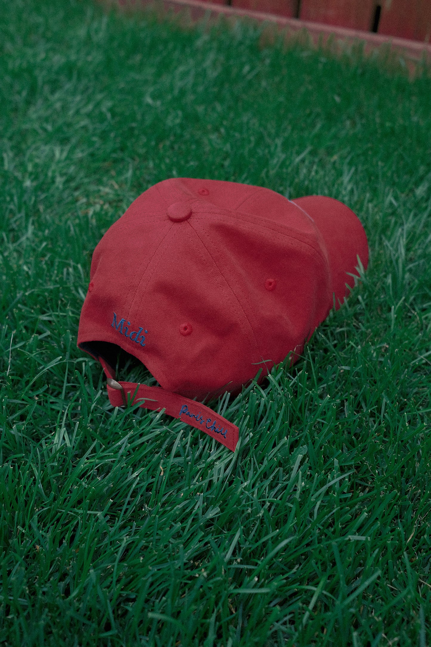 Back of HÔTEL827 Sun Kissed baseball cap in chilli on the grass.
