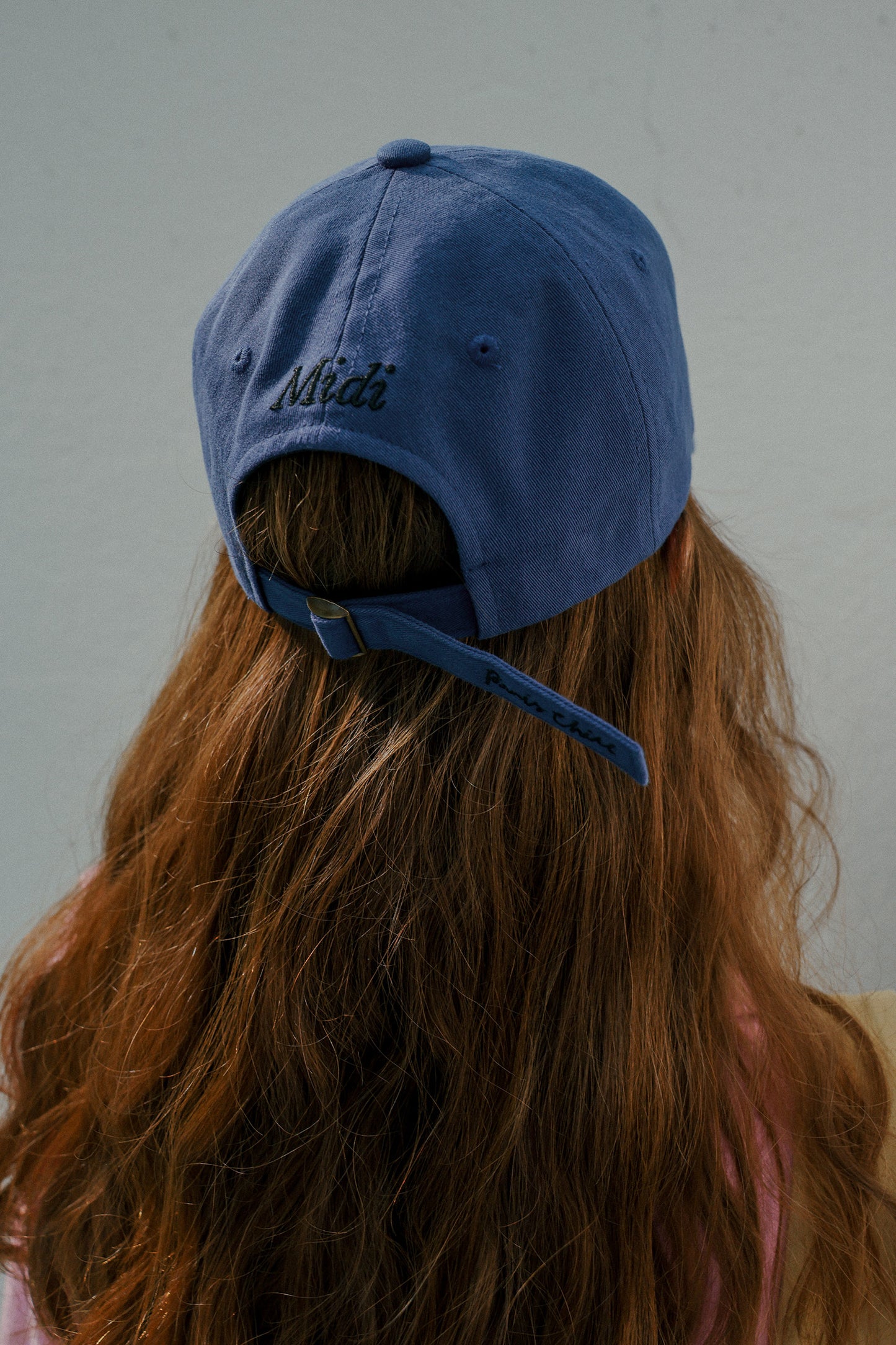 Back view of a woman with brown hair wearing HÔTEL827 Sun Kissed blue baseball cap