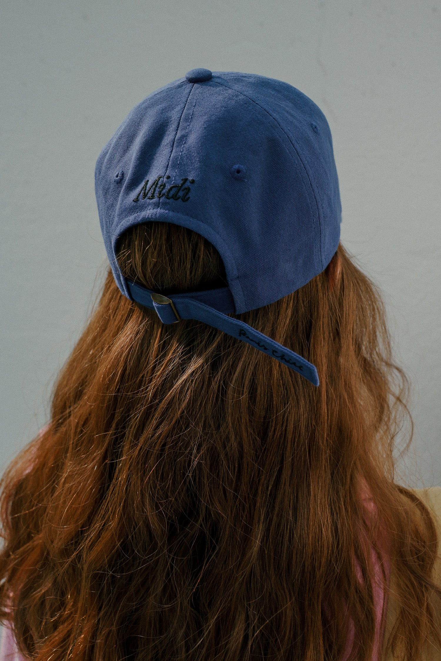 Back view of a woman with brown hair wearing HÔTEL827 Sun Kissed blue baseball cap