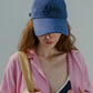 Woman wearing HÔTEL827 Sun Kissed blue baseball cap in beach wear. 