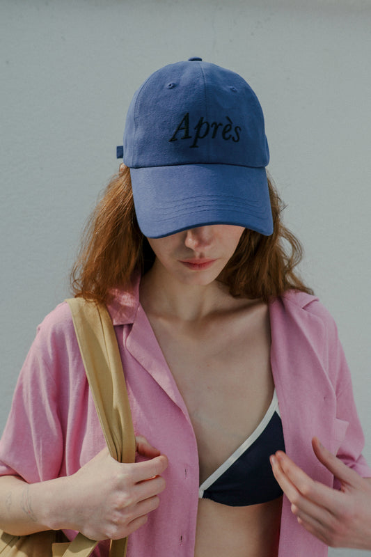 Woman wearing HÔTEL827 Sun Kissed blue baseball cap in beach wear. 