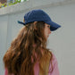 Side angle of Woman wearing HÔTEL827 Sun Kissed blue baseball cap in casual street style